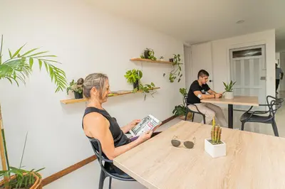 two people sitting at a table reading a book at Tu Espacio Privado en Medellín E in Medellín
