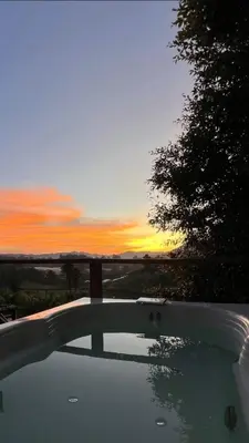 a view of a sunset from a bath tub with a tree at Alto Paraíso Glamping 