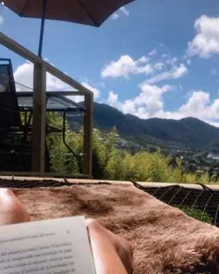 a person reading a book on a table with an umbrella at Alto Paraíso Glamping 