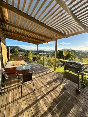 a wooden deck with a grill and a table at Alto Paraiso Glamping 