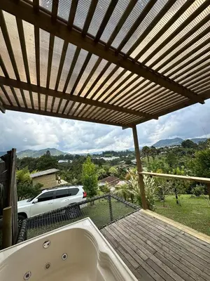 a bath tub sitting under a wooden roof with a car at Alto Paraiso Glamping 