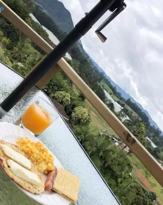 a table with a plate of food and orange juice at Alto Paraiso Glamping 