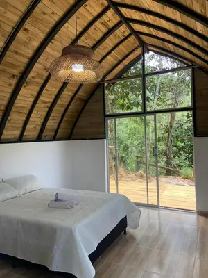 a bedroom with a bed in a room with large windows at Glamping A-MAR in Cocorná