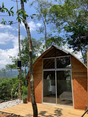 a small house with a large window on a wooden deck at Glamping A-MAR in Cocorná