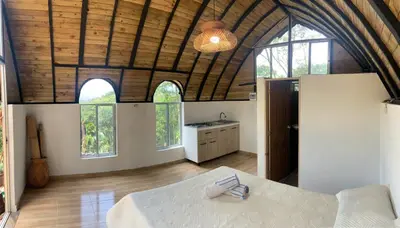 a bedroom with a bed and a kitchen with windows at Glamping A-MAR in Cocorná