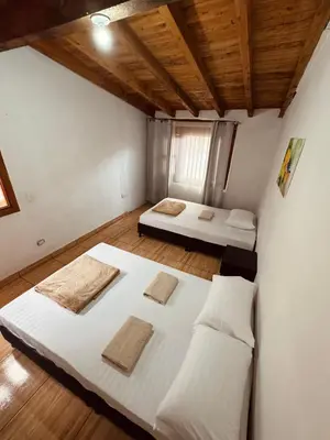two beds in a room with white walls and wooden floors at Next to the airport - cute home in Rionegro