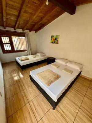two beds in a room with wooden floors at Next to the airport - cute home in Rionegro