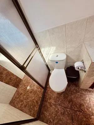 a bathroom with a toilet and a glass shower stall at Next to the airport - cute home in Rionegro
