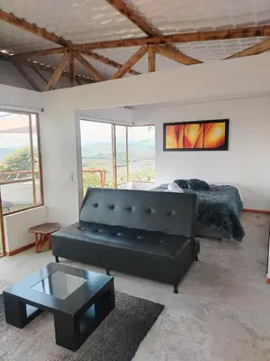 a living room with a black leather couch and a bed at Glamping Orosierra in Chinchiná