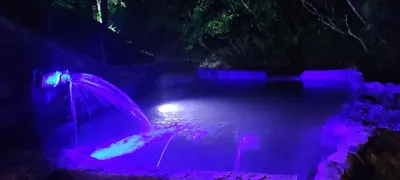 a person holding an umbrella in a pool at night at Glamping Río Claro in Doradal