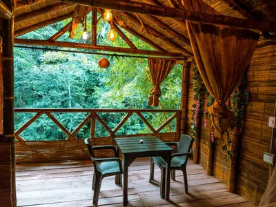 a table and chairs on the porch of a cabin at Glamping Río Claro in Doradal