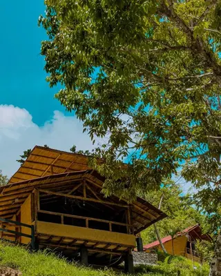 a wooden barn sitting on top of a lush green field at Glamping Río Claro in Doradal