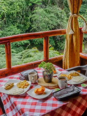 a picnic table with plates of food on a deck at Glamping Río Claro in Doradal