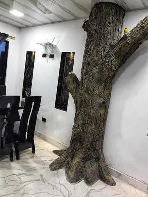 a large tree trunk sitting next to a wall at Casa Del Árbol in Doradal