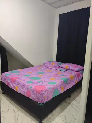 a small bed in a bedroom with a purple comforter at Casa Del Árbol in Doradal