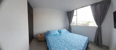 a bedroom with a bed with a blue comforter and a window at Casa Colibrí Hospedaje Manizales a 2 min del Cable y 1 min Zona G in Manizales