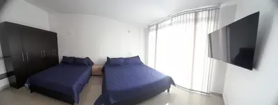 a bedroom with two beds and a tv and a window at Casa Colibrí Hospedaje Manizales a 2 min del Cable y 1 min Zona G in Manizales