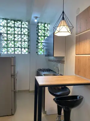 a kitchen with a wooden table and two black stools at Casa Colibrí Hospedaje Manizales a 2 min del Cable y 1 min Zona G in Manizales