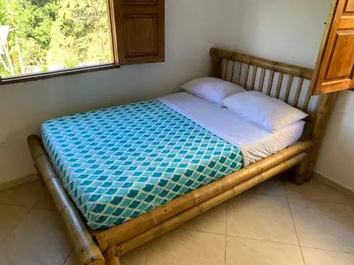 a wooden bed in a room with a window at Jardín de la Inmaculada - a 8min del parque in Jardin