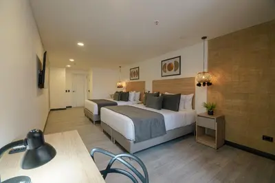 a hotel room with two beds and a table at First Class Hotel in Medellín