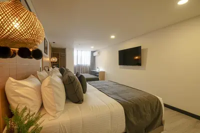 a bedroom with a bed with pillows and a television at First Class Hotel in Medellín