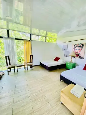 a room with two beds and chairs and windows at Cabaña Tierra Verde eje Cafetero in Manizales