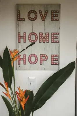 a sign that reads love home hope next to a plant at Cabaña Tierra Verde eje Cafetero in Manizales