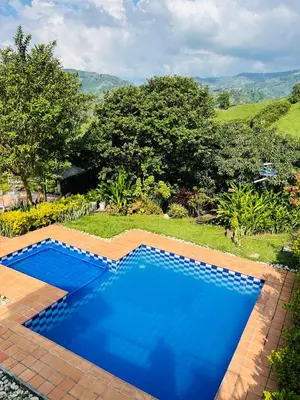 a large blue swimming pool in a yard at Cabaña Tierra Verde eje Cafetero in Manizales