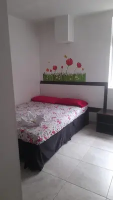 a bed in a room with red flowers on the wall at El Amanecer La 27 in Manizales