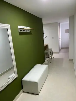 a room with a green wall with a bench and a mirror at Urban 102 in Manizales