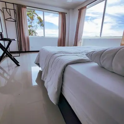 a bedroom with a large bed with windows at Hotel Ocaso Marinilla in Marinilla