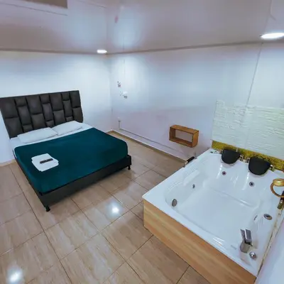 a room with a bed and a bathtub and a bath tub at Hotel Ocaso Marinilla in Marinilla