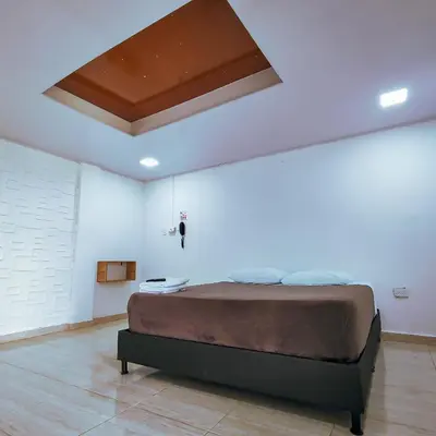 a bedroom with a large bed in a white room at Hotel Ocaso Marinilla in Marinilla