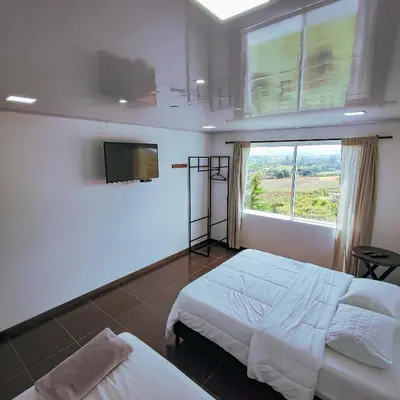 a bedroom with two beds and a window at Hotel Ocaso Marinilla in Marinilla