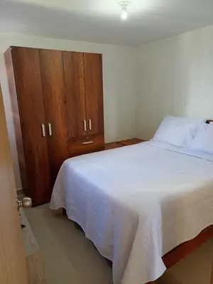 a bedroom with a white bed and a wooden cabinet at Lindo Apartamento para estadía familiar in Rionegro
