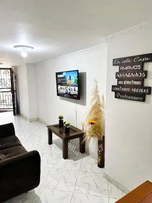 a living room with a couch and a tv on a wall at Acogedor apartamento cerca al centro de Medellin in Medellín