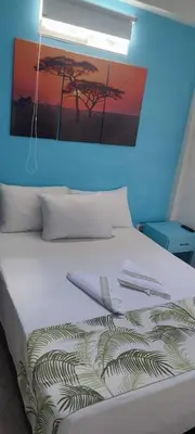 a bedroom with a white bed with a painting on the wall at cabaña82 in Puerto Triunfo