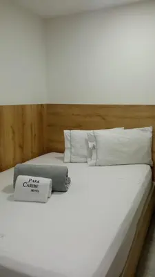a bed with white sheets and pillows on it at Hotel Park Caribe in Medellín