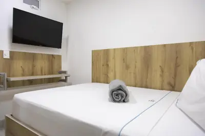 a bedroom with a white bed and a flat screen tv at Hotel Park Caribe in Medellín