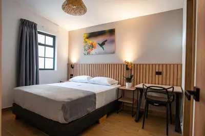 a bedroom with a bed and a table with a chair at Vita Hotel Boutique - Aire Acondicionado & Desayuno in Medellín