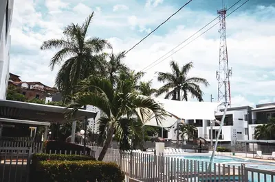 a pool with palm trees and a white fence at Encantador Apartamento Ciudadela in Santa Fe de Antioquia