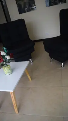 a room with two chairs and a table with flowers at Encantador Apartamento Ciudadela in Santa Fe de Antioquia