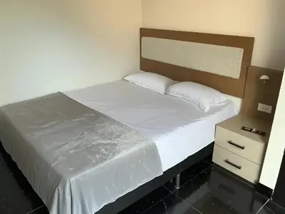 a bed with white sheets and a wooden headboard in a bedroom at Aparta Suite Torre De Prado 501 in Medellín