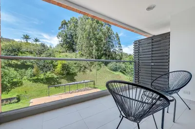 a balcony with a chair and a large window at PORTANOVA Suites by ADVENTU in Rionegro