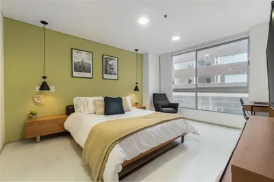 a bedroom with a large bed and a chair at PORTANOVA Suites by ADVENTU in Rionegro