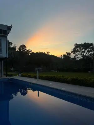 a swimming pool with a sunset in the background at La Martina Palestina in Palestina