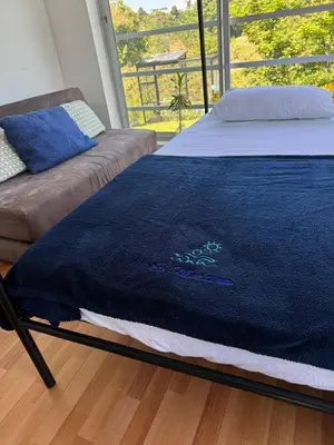 a bed with a blue blanket on it in a room at La Martina Palestina in Palestina