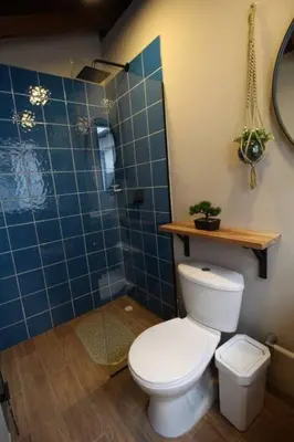 a bathroom with a toilet and a blue tiled shower at Estudio sector Universidad de Medellín - ONE205 By Roots Rentals in Medellín