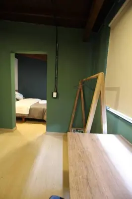 a bedroom with a bed and green walls and a wooden floor at Estudio sector Universidad de Medellín - ONE205 By Roots Rentals in Medellín
