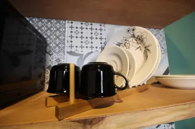 a shelf with two coffee cups and plates on it at Estudio sector Universidad de Medellín - ONE205 By Roots Rentals in Medellín